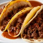Three crispy birria tacos filled with tender meat and served with a side of flavorful dipping broth.