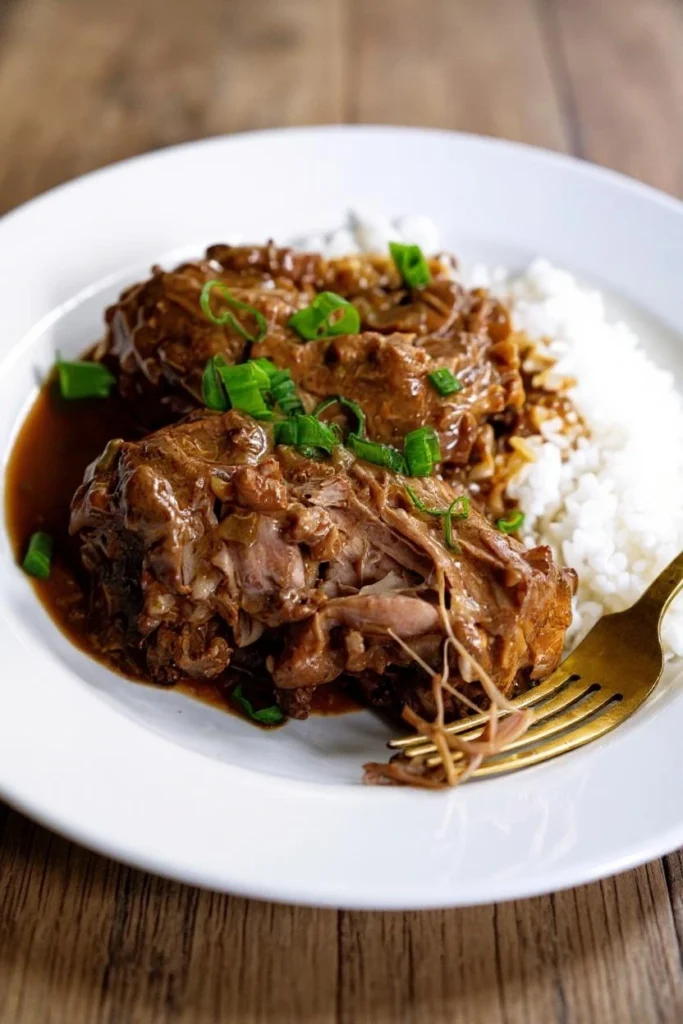 Close-up of tender, braised turkey necks smothered in a rich, thick, brown gravy with visible onions, bell peppers, and fresh green onions in a large cooking pot.