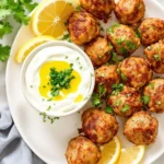 Juicy turkey meatballs with parsley and dipping sauce on a white plate